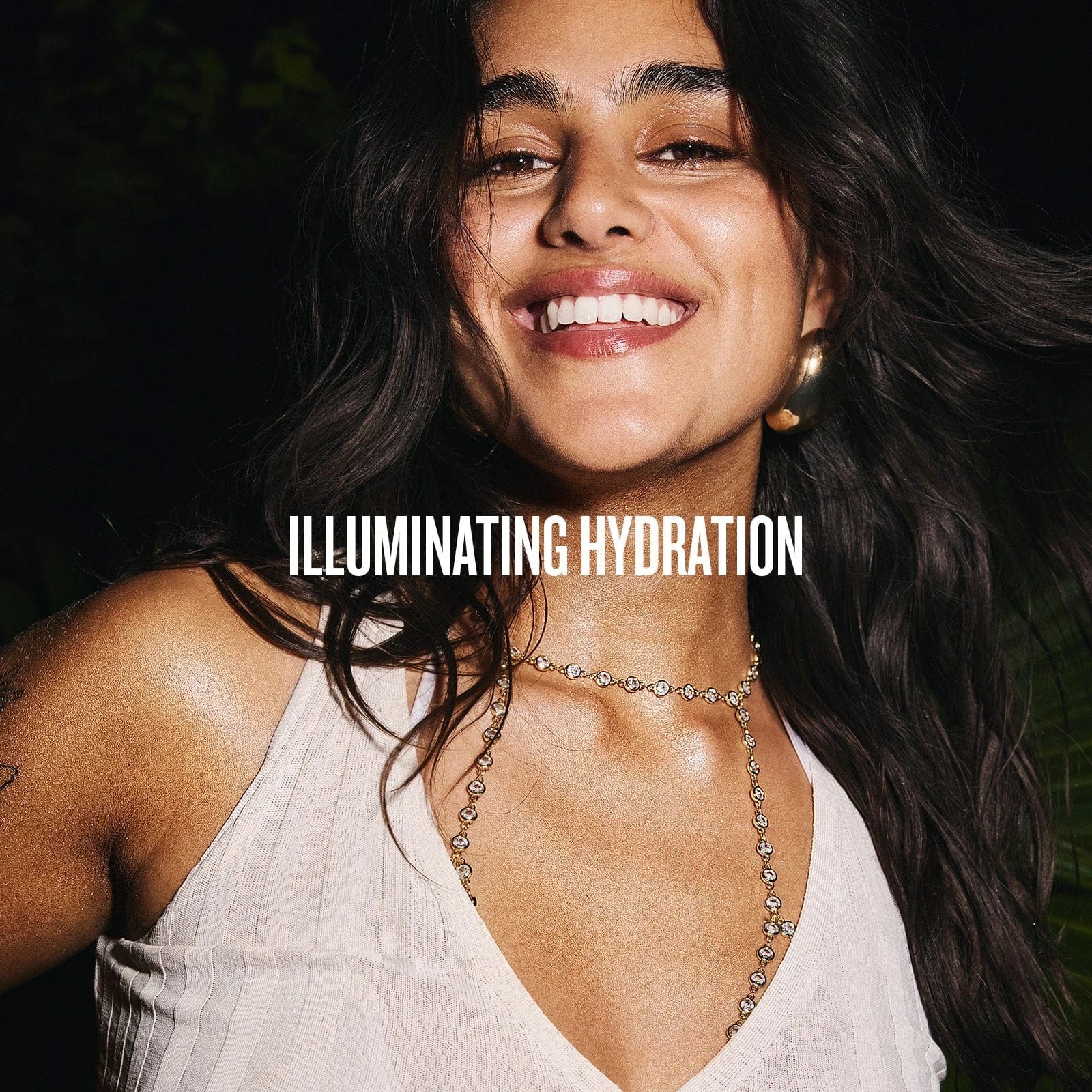 Image on text reads illuminating hydration. This image is of a model smiling wearing the glowmotions body oil and having shimmery skin